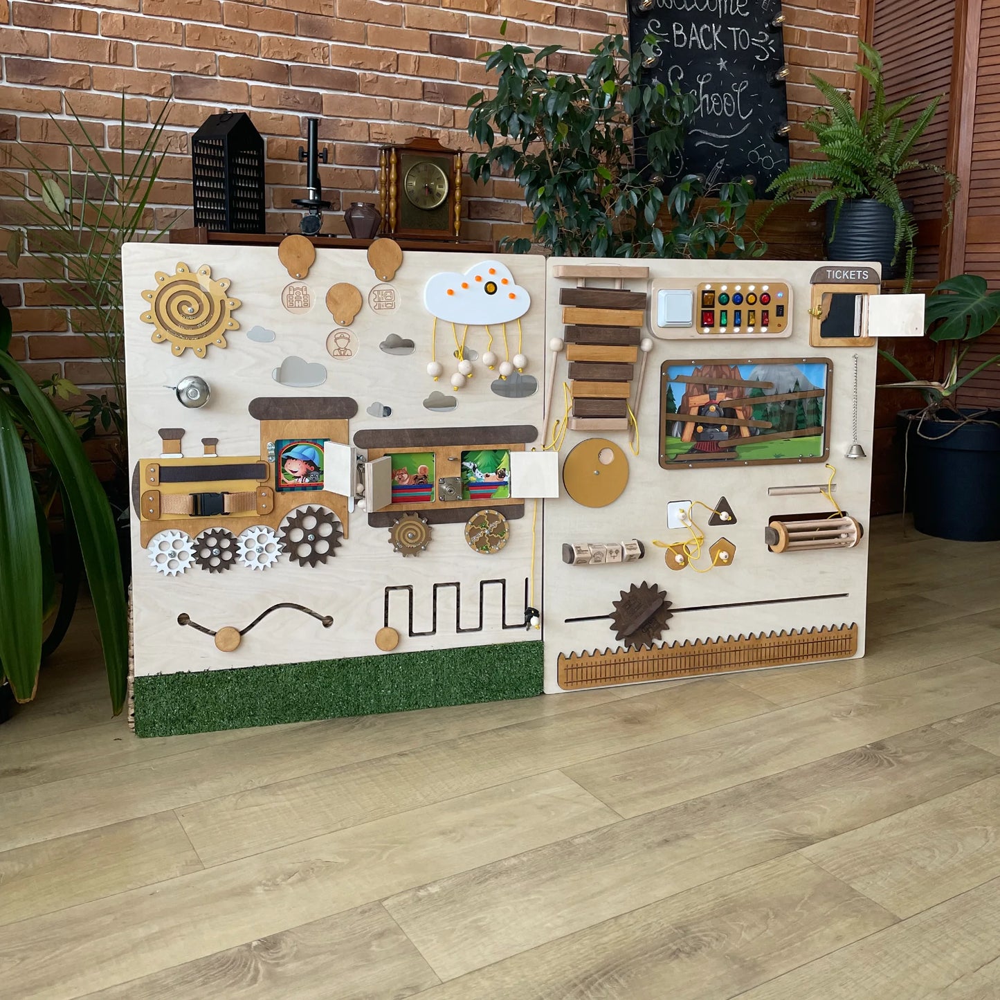 Interactive train-themed sensory wall panel with hidden photo windows, gears, lights, switches, a bell, and xylophone. Fun educational tool for schools and therapy spaces