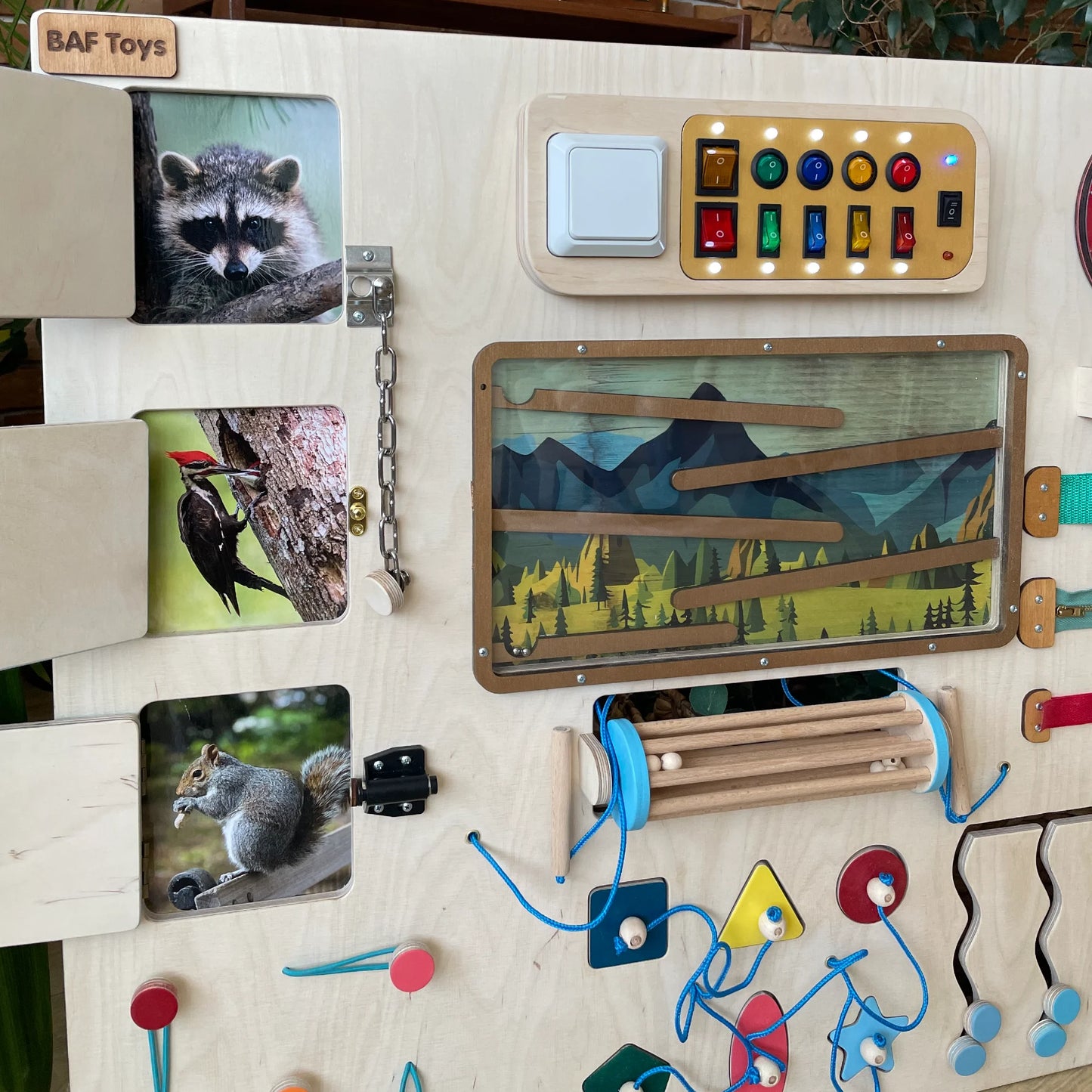 Child playing with large interactive mountain-themed sensory wall full of educational wooden elements.