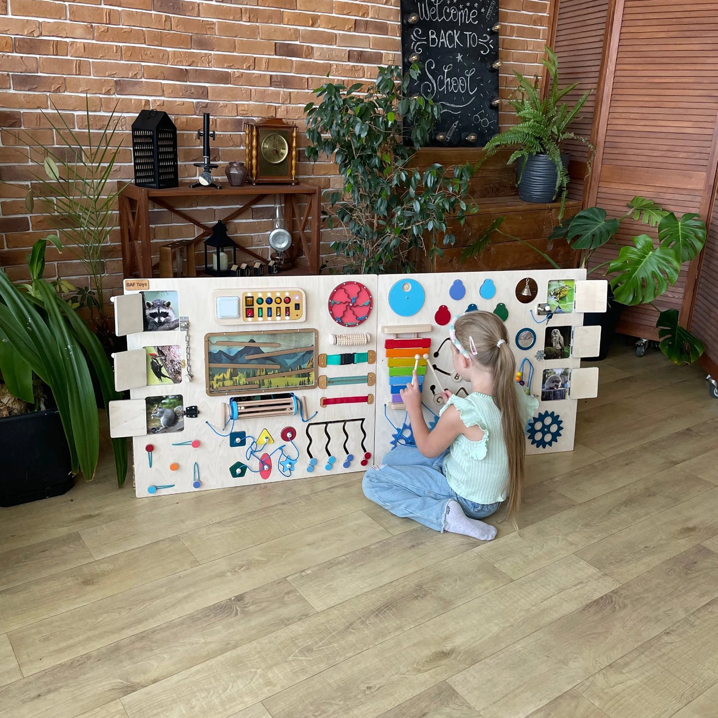 Girl playing with bright sensory wall panel with mountain theme, LED lights, and Montessori elements – perfect for therapy or classrooms