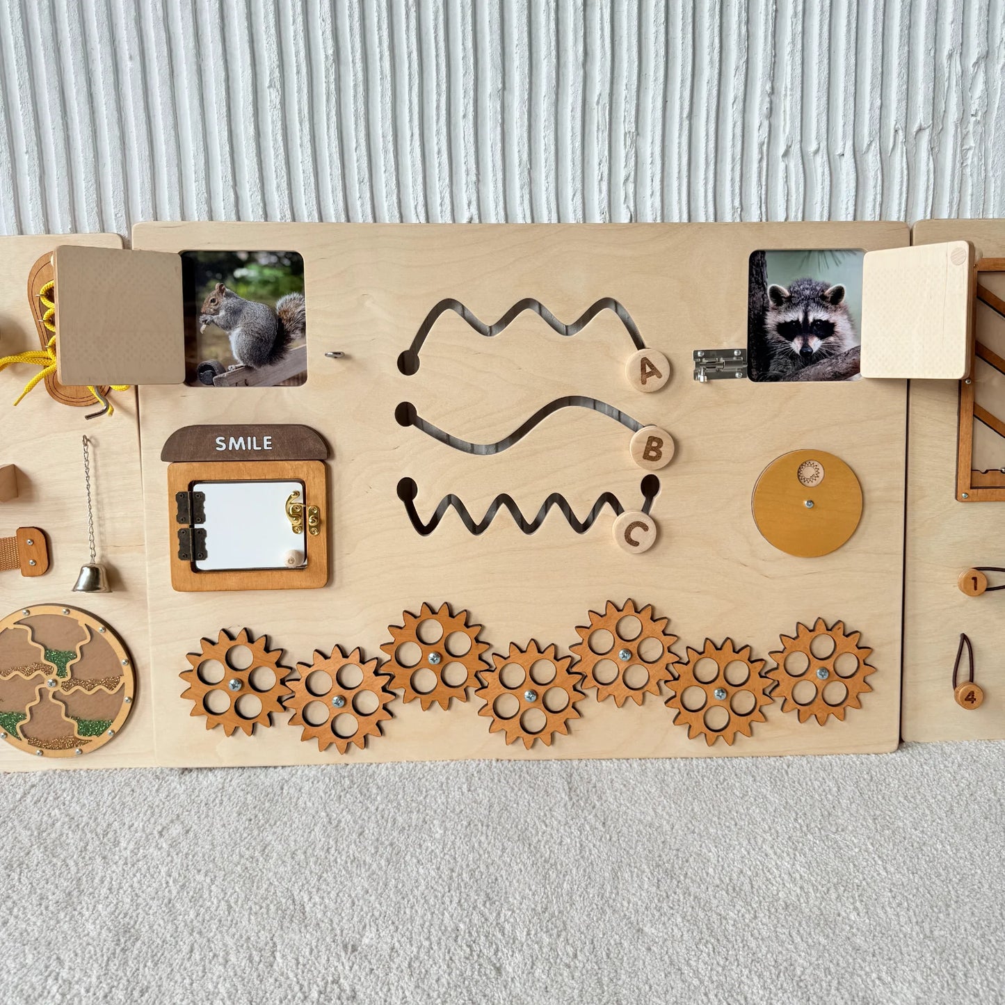 Middle part of busy board with gears, animal peekaboo doors, mirror and sensory tracing elements