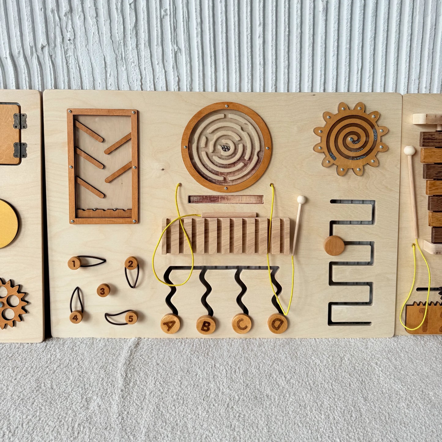 Natural sensory panel with maze, spiral spinner, sliders, and zigzag tracing elements for hand-eye coordination