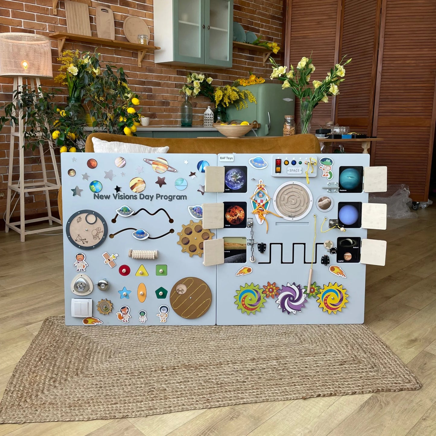 Sky Blue sensory wall panel with space theme, used in special needs day program. Features lights, doors, switches, and fine motor activities