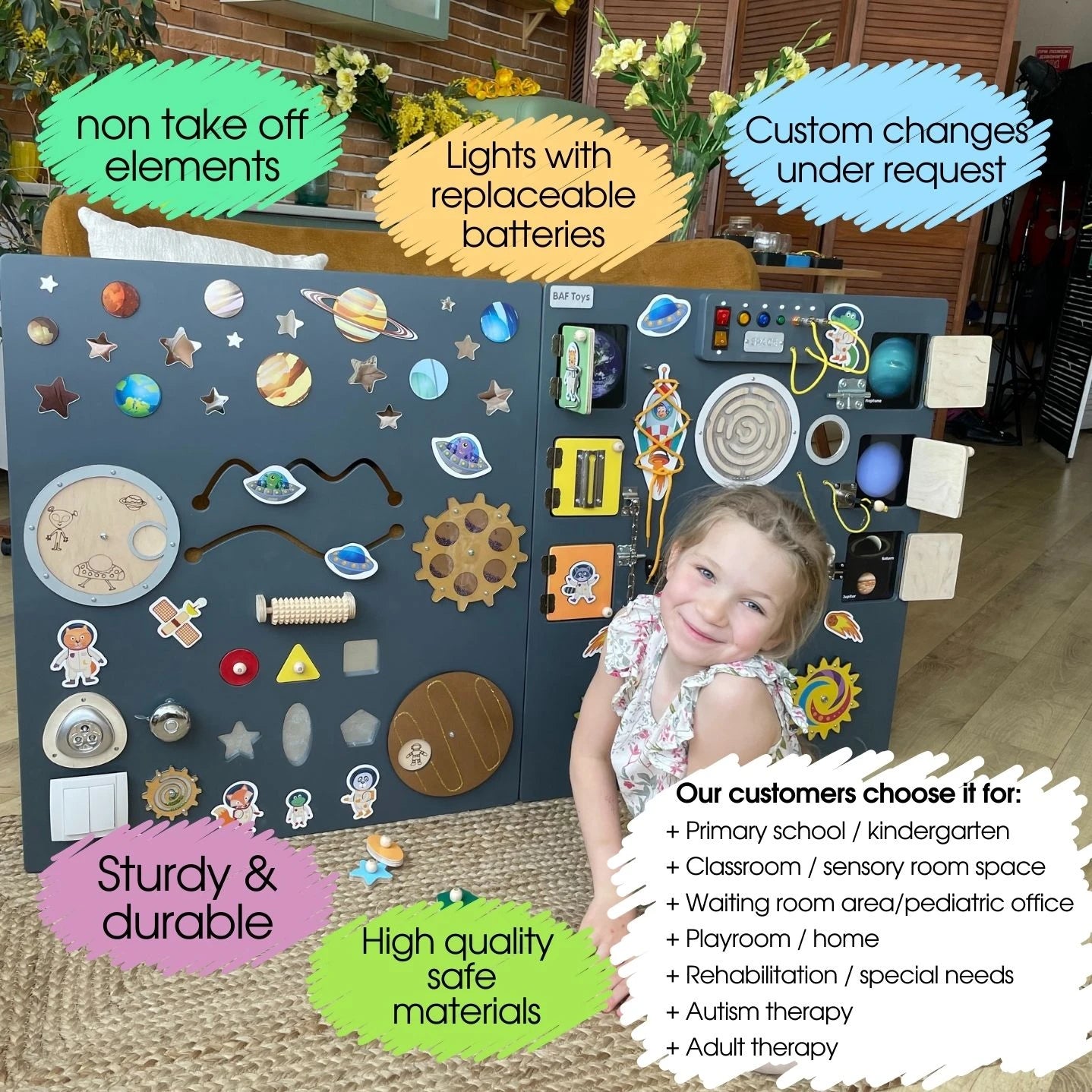 Smiling girl next to a large space-themed sensory wall panel with labeled features such as non-take-off elements, replaceable batteries, custom changes, and recommended uses for schools, clinics, and therapy
