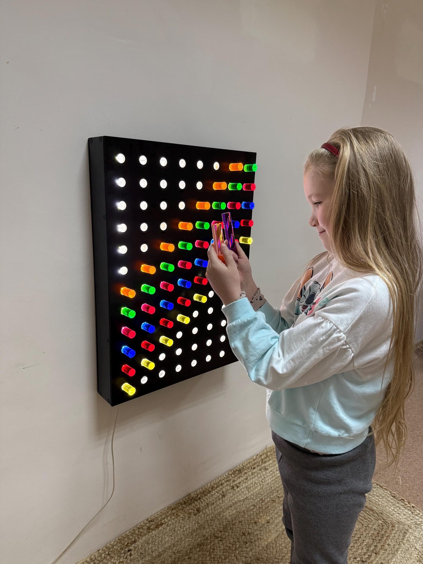 Child holding acrylic rods near Giant Light Peg Board With Acrylic Rods | Light Panel Sensory Wall – interactive LED sensory activity panel for classroom and playroom
