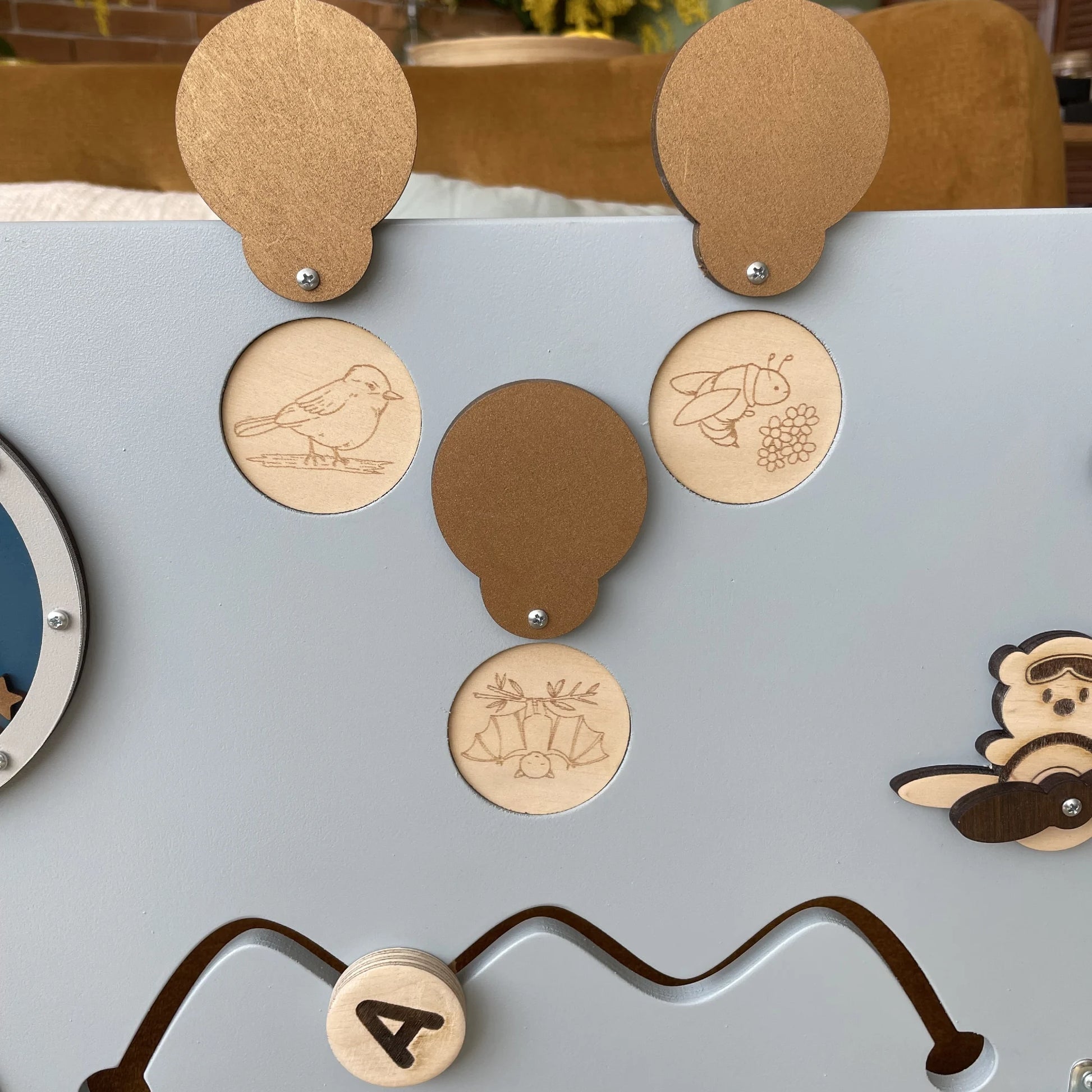 Close-up of right side of sensory wall panel featuring animal flaps, gears, and tracking mazes
