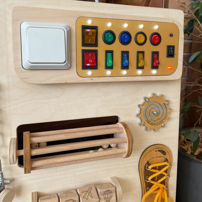 Close-up of the LED light switches section on the wooden sensory wall panel for tactile stimulation and cause-effect learning.